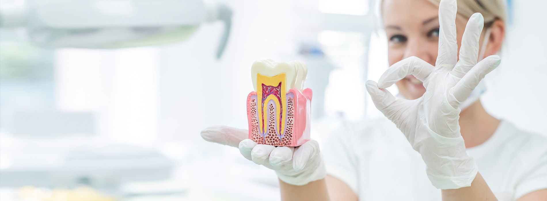 A dental hygienist in a white lab coat holding up a toothbrush with a cartoon character on it against a blurred background.